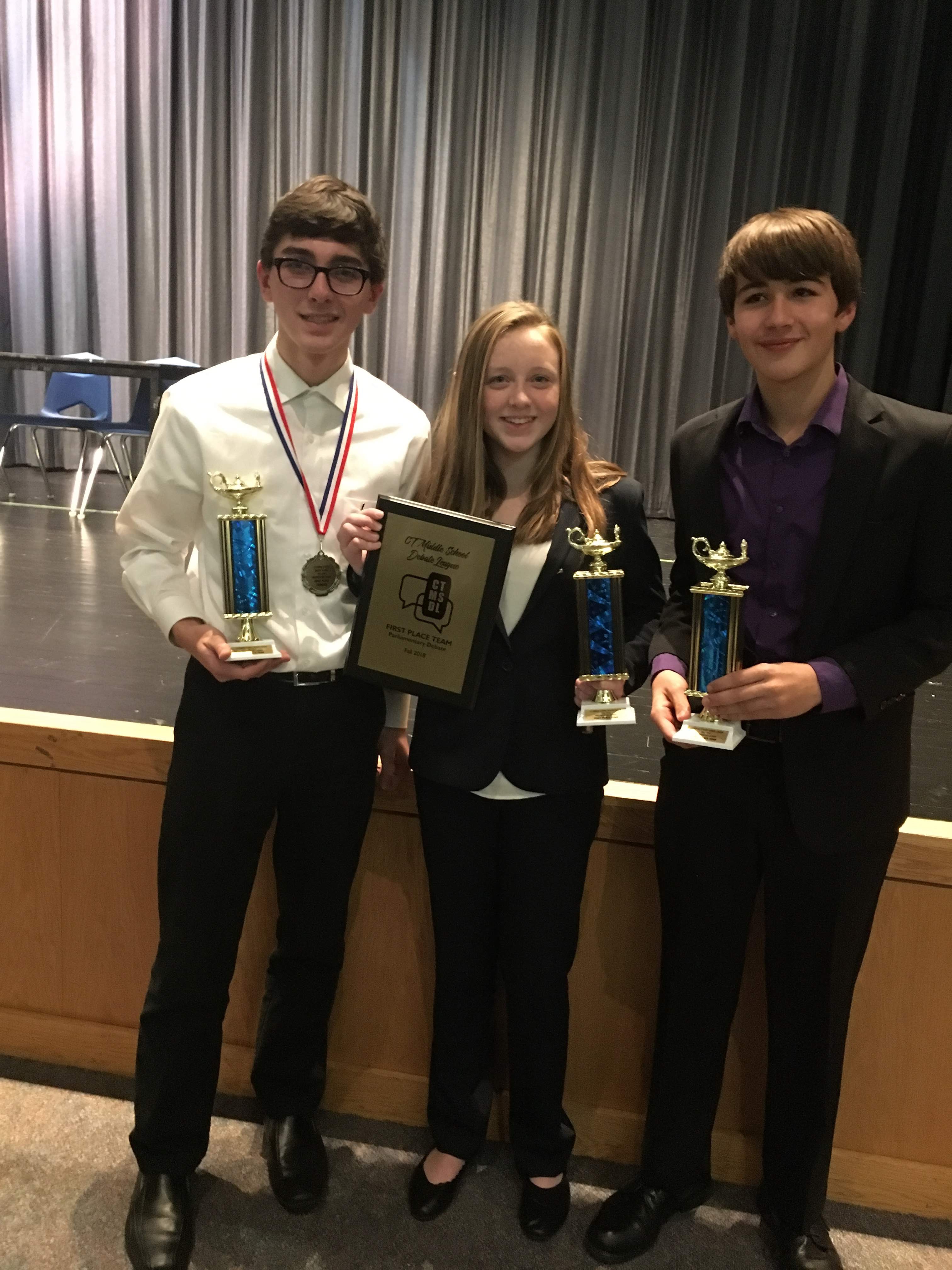 Matt Tobin holding 3 trophies from the English in Action Middle School Debate Championship